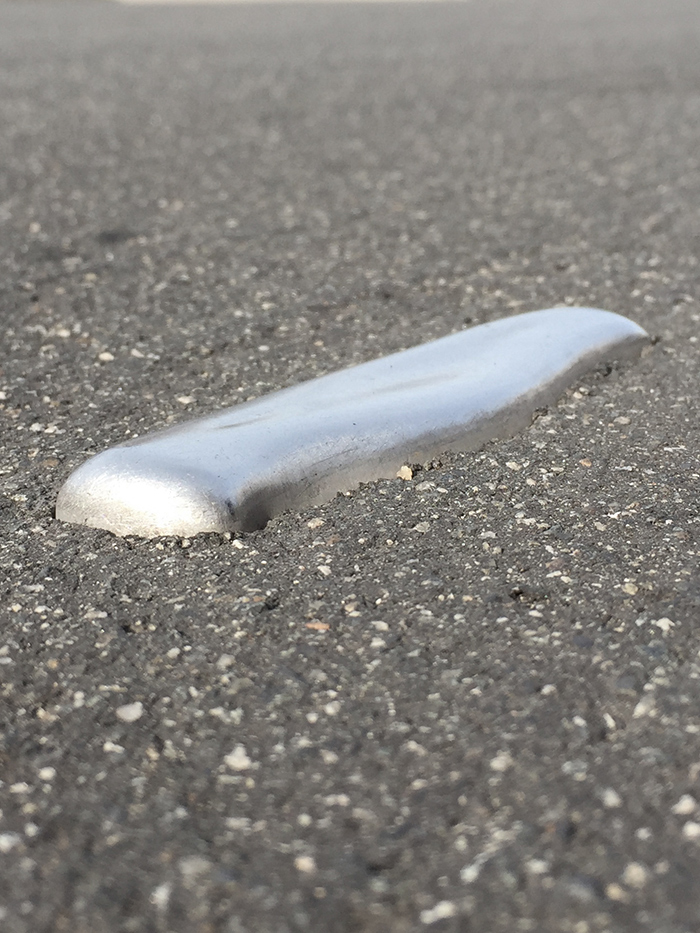 metal object (could be a knife handle?) embedded into asphalt