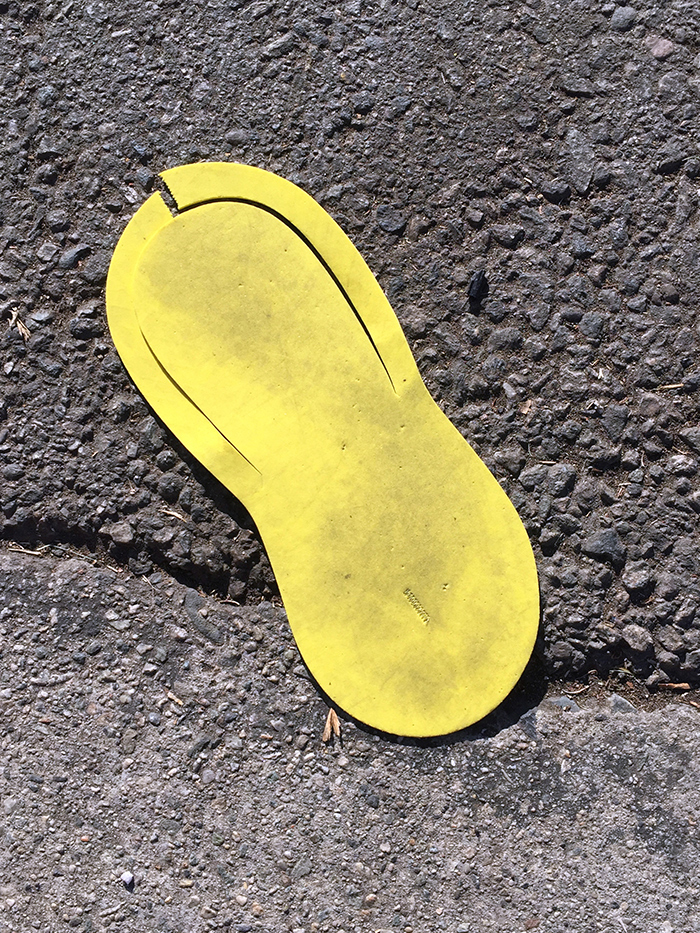 flattened yellow manicure single-use sandal in the road