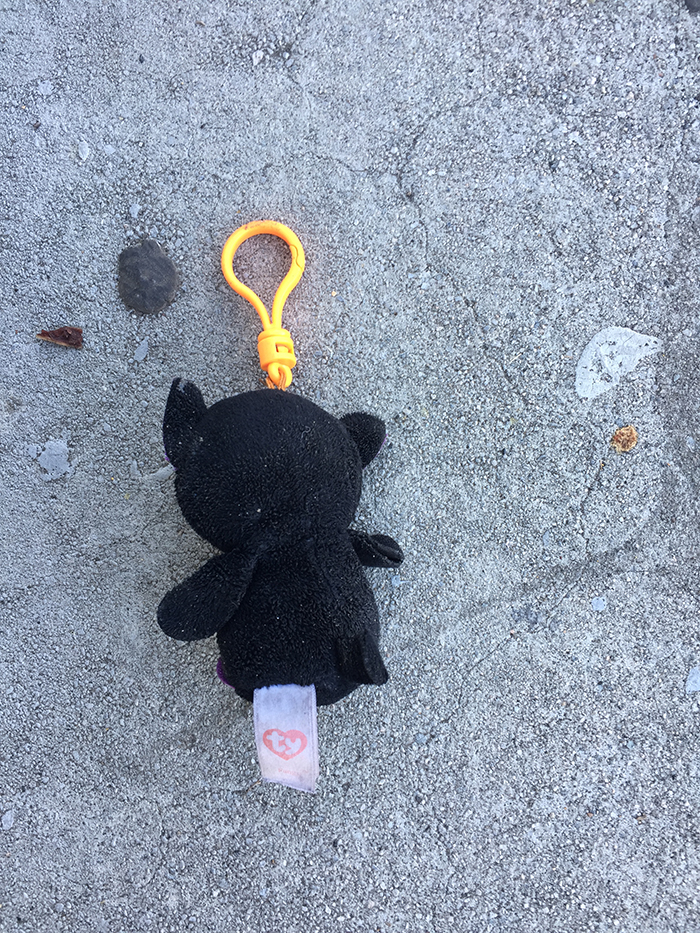 black plush toy face-down with orange keychain loop