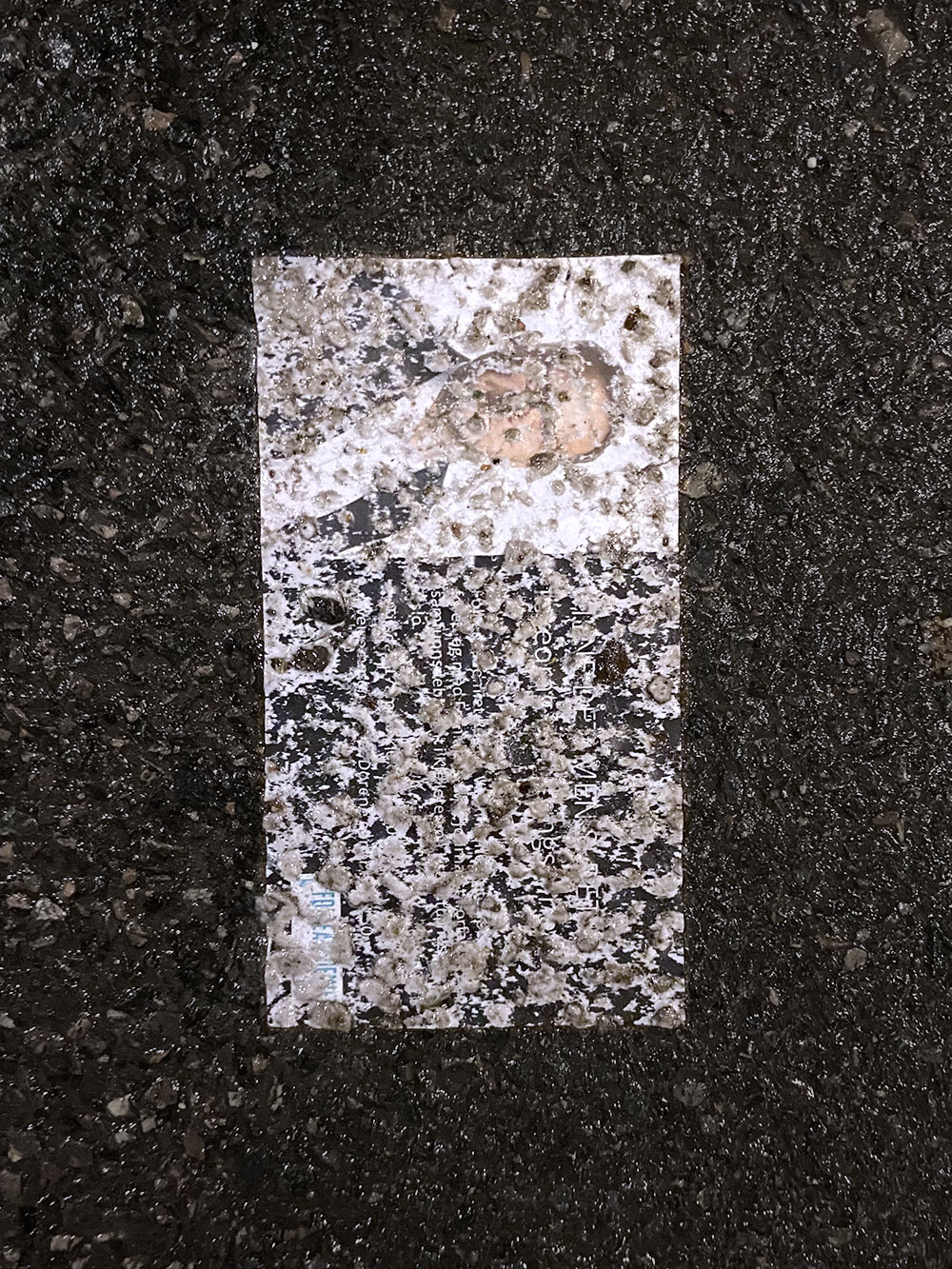 smashed business card with a white man's face on it